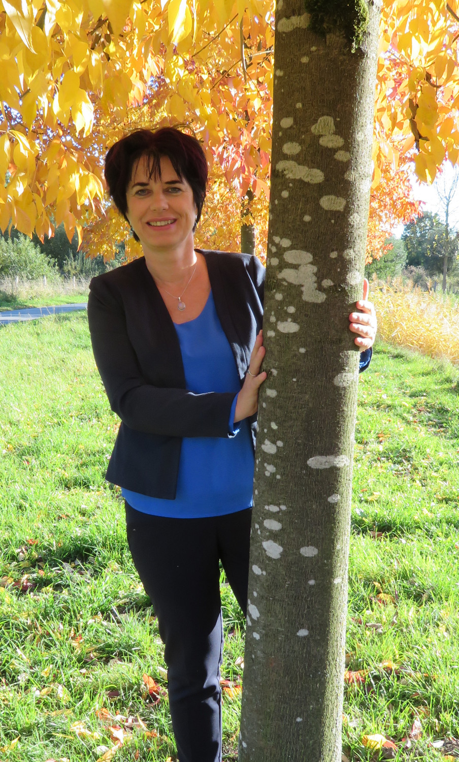 Miriam Georg steht unter einem herbstlich gefärbten Baum